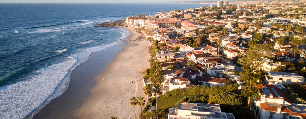 Aerial view of houses lining the shore of a beach near San Diego State