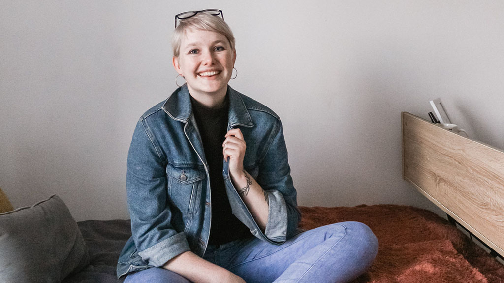 student sitting on her bed in dorm room