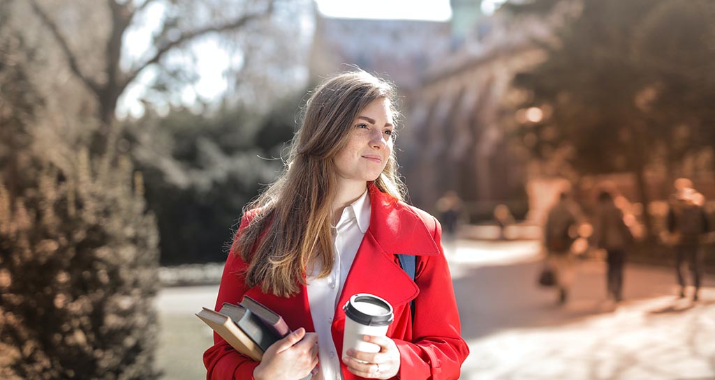 college student holding books and coffee