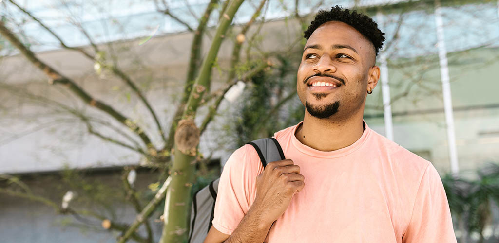 College transfer student smiling and carrying a backpack.