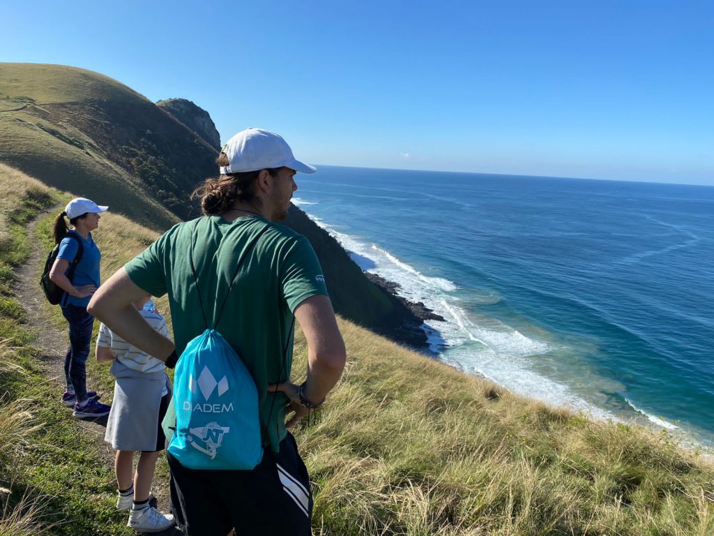 Girl standing on a cliff overlooking the ocean.