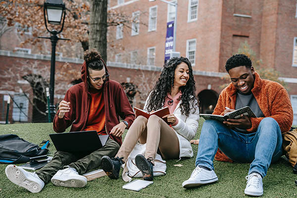 College Students sitting in grass and laughing.