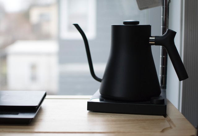 A black kettle sitting on a wooden table.