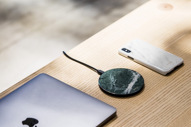 A desk holding a MacBook, a portable charger, and a phone.