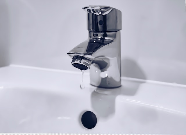 Silver faucet with a small droplet of water leaking.