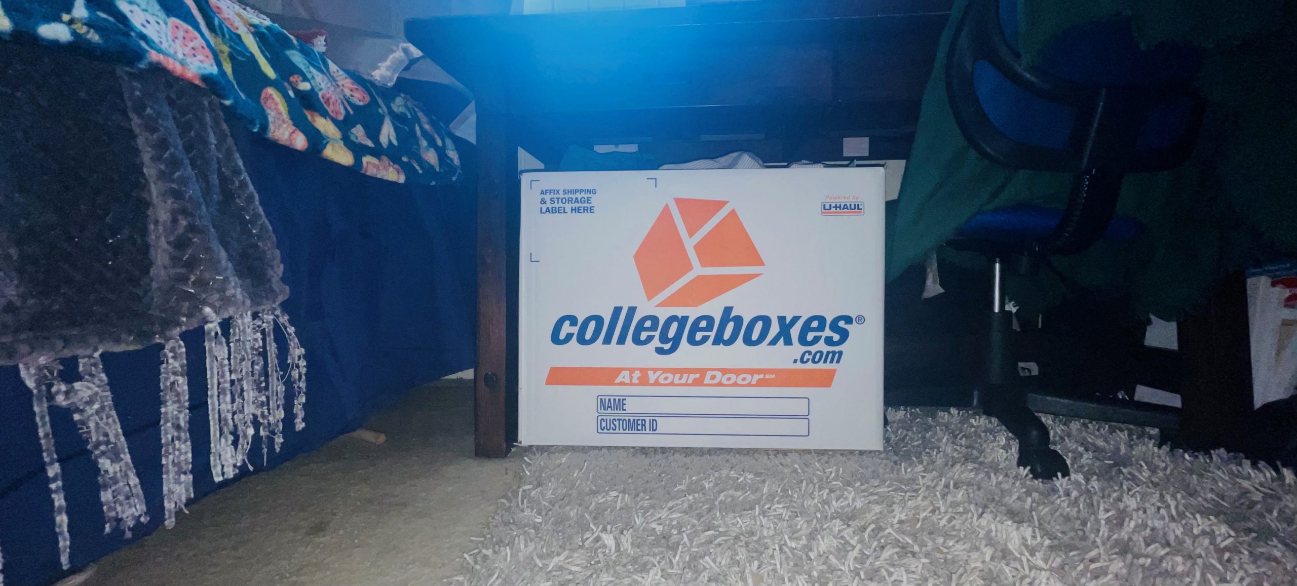 Collegeboxes Signature Box sitting on a rug under a wooden desk