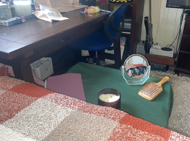 A makeshift nightstand holding a brush, mirror, tablet, and a candle