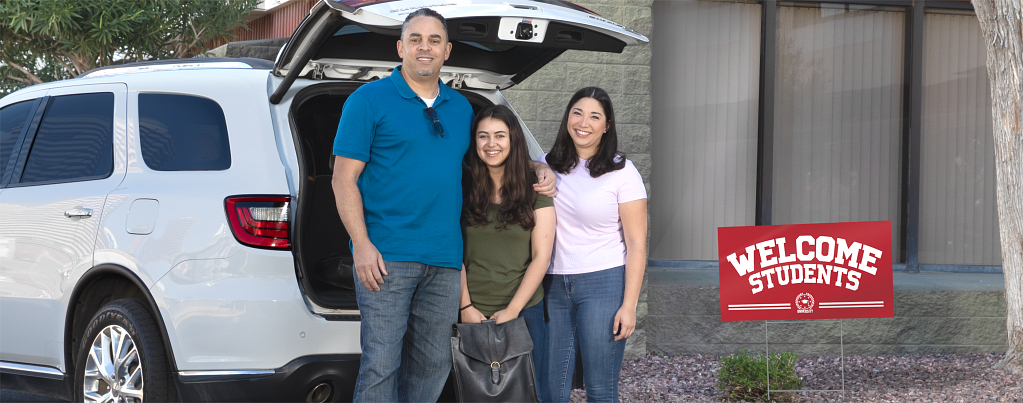 A mother, father, and daughter stand outside their car.