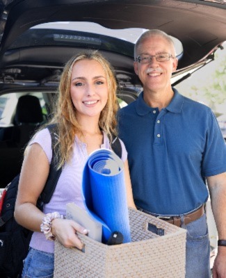 An older man srands next to a younger woman holding a box.