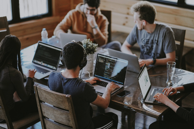 Four students sitting at a library table with their computers.