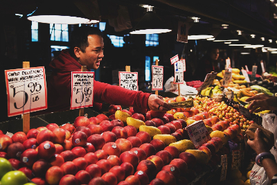 Man standing over an apple stand and handing someone their change