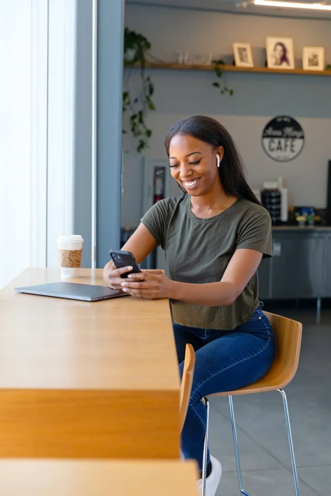 Girl in t-shirt and jeans sitting at a desk looking at her phone