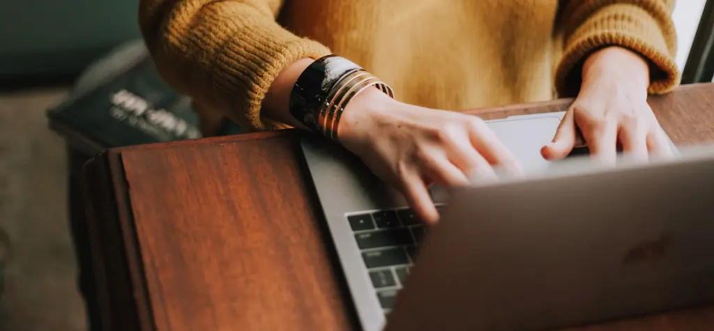 Woman in yellow sweater typing on her laptop