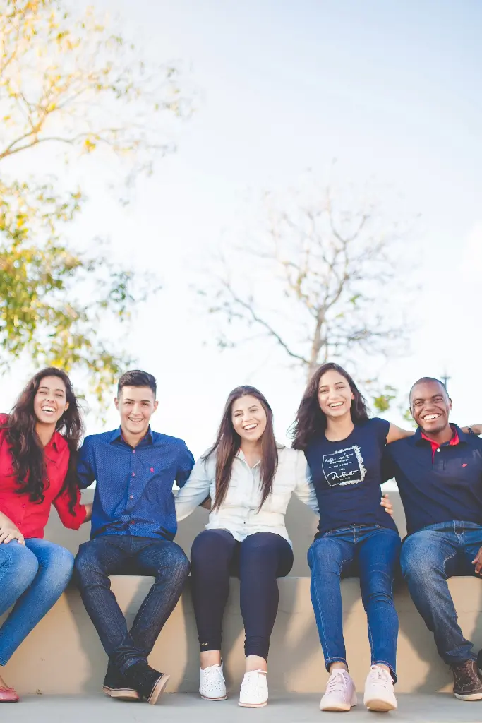 5 students sitting in a line outside