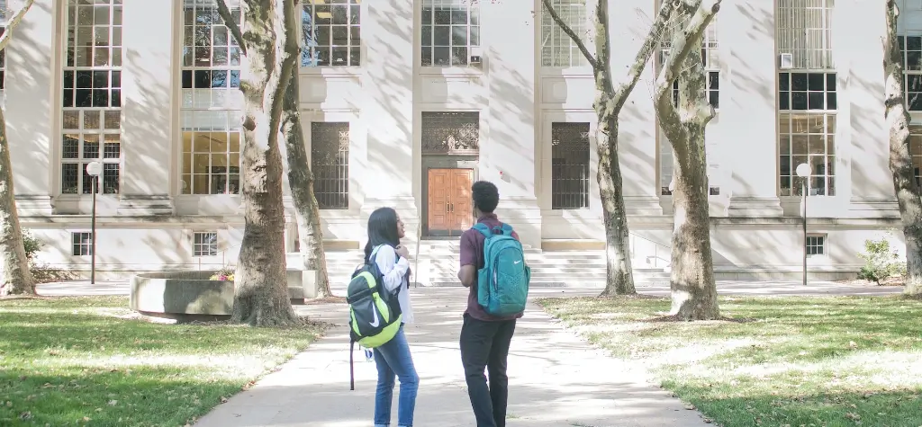 Two students standing in front of a large stone building