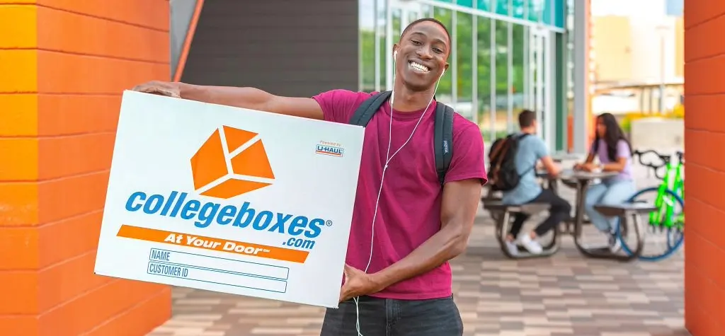 Young man smiling with a Collegeboxes box under his arm