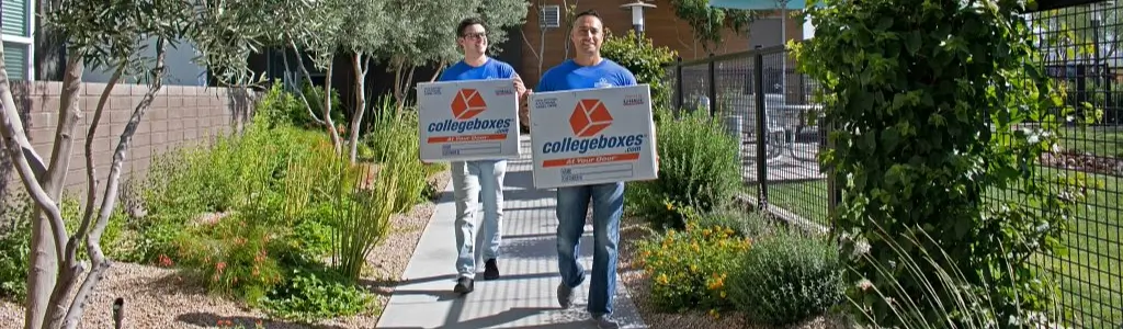 Two men walking down the sidewalk with boxes in hand