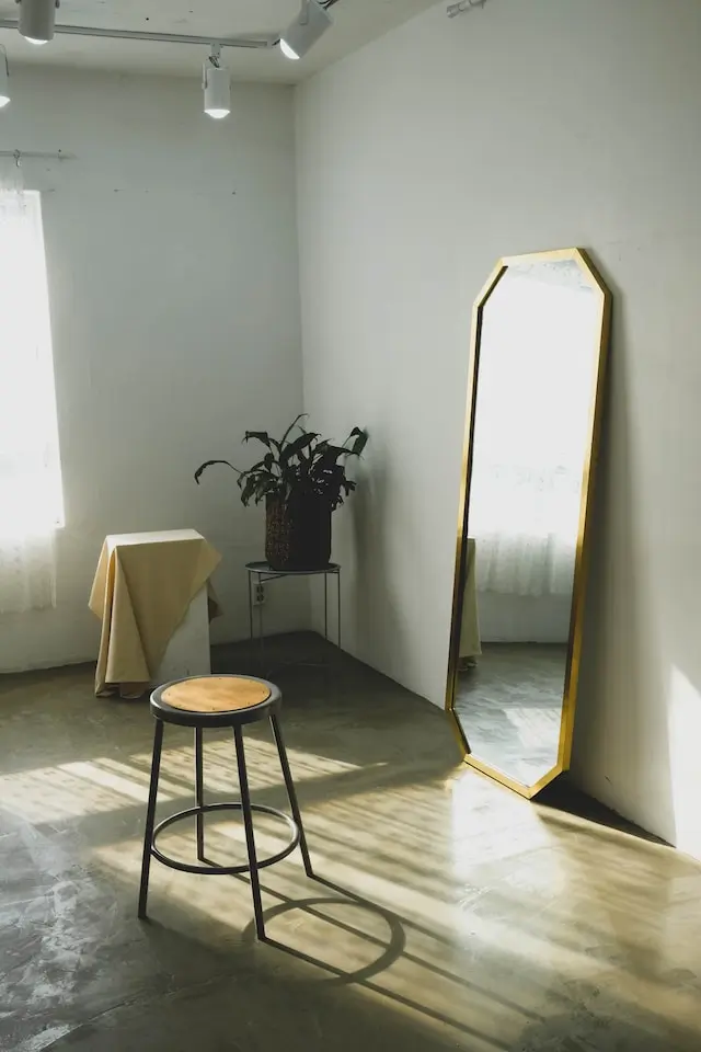 Mirror leaning against the wall next to a stool