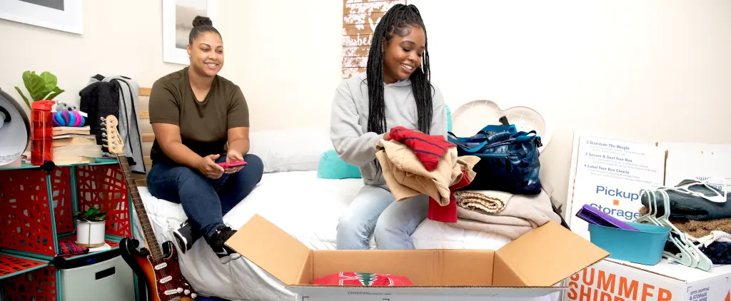 Two college students pack their dorm room before moving out.