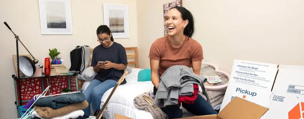 Two girls in a dorm and packing boxes