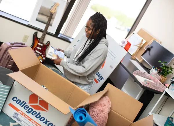 Young woman packs up her dorm room essentials.