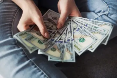 Woman's hands holding multiple hundred dollar bills