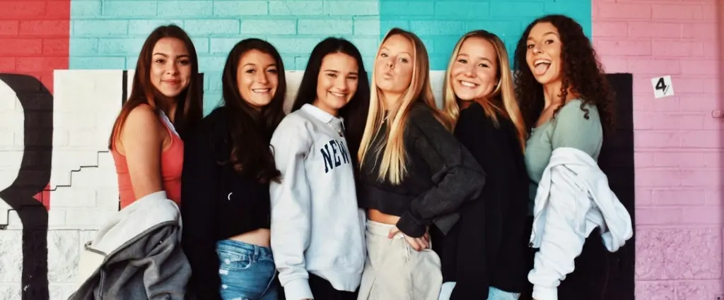 6 girls lined up against a colorful wall