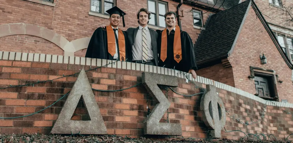 Three men standing behind a Greek letter sign