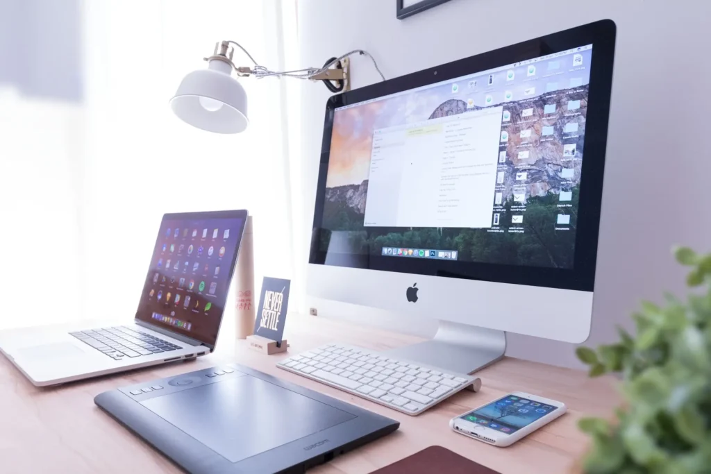 An apple computer, laptop, and other tech on a desk