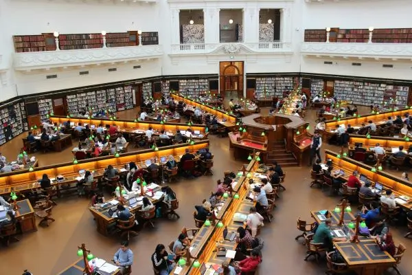 Wide view of a college library with many students at the tables
