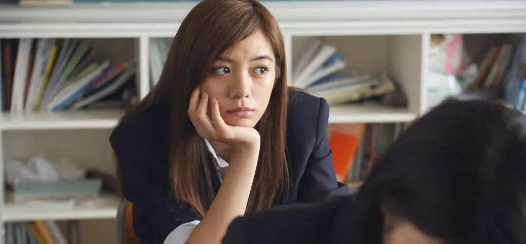 Girl sitting at a desk with her chin in her hand.