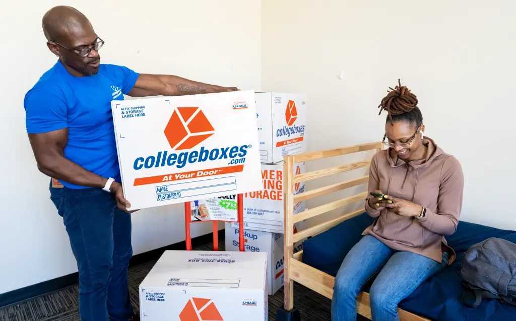 Collegeboxes movers help move a student into her dorm room.