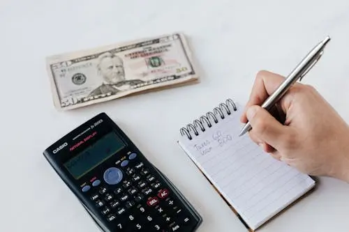A calculator, 50 dollar bill, and a notebook.