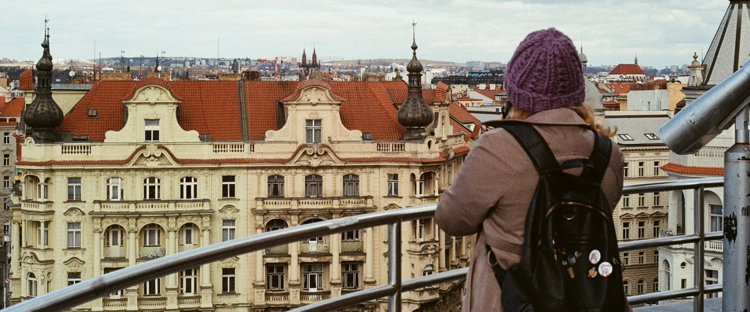 A girl standing at the balcony looking over to a castle