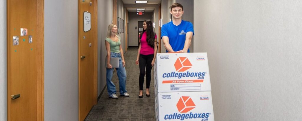 Collegeboxes employee using a utility dolly with boxes walking through a dorm hall